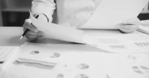 Mano con un lápiz sobre documentos impresos.
